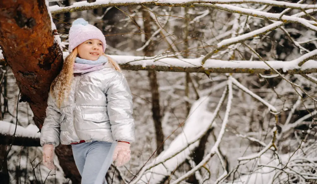 cute little girl in a silver winter jacket outside during winter