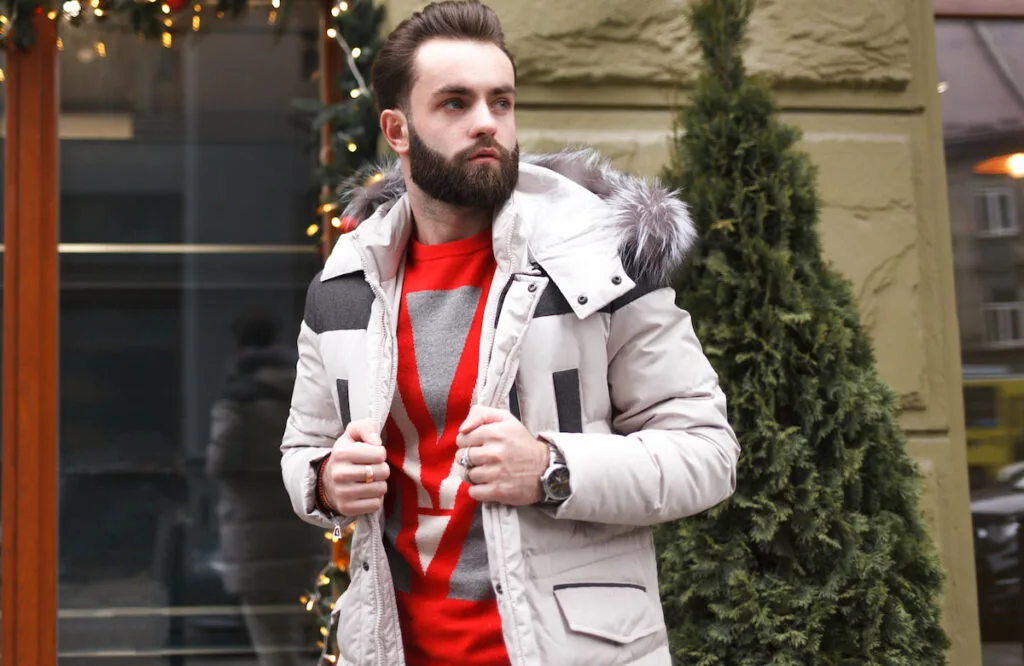 handsome man with beard in a winter jacket with fur outdoor