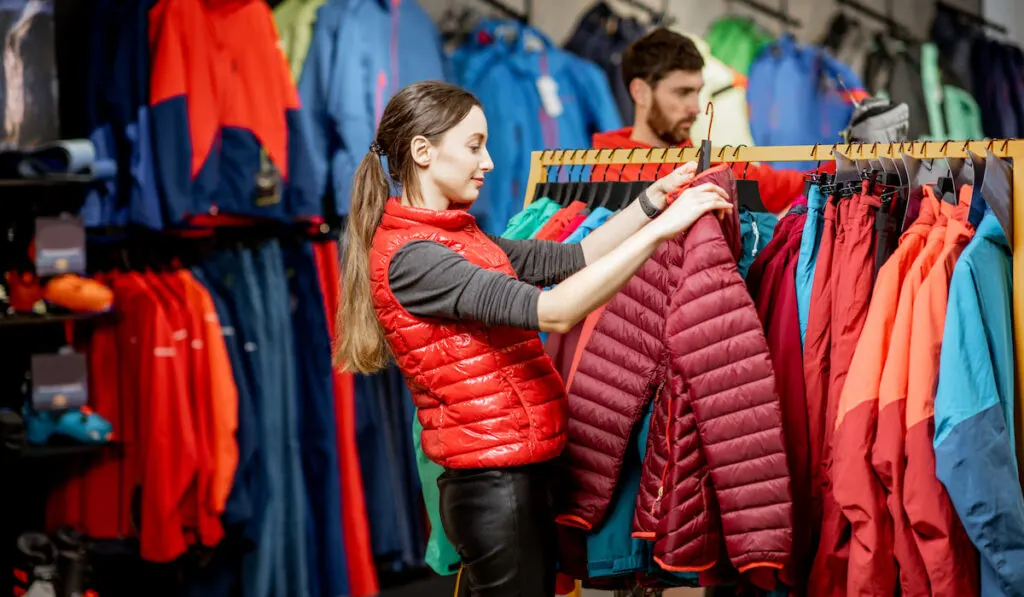 woman choosing winter jacket in thrift store 