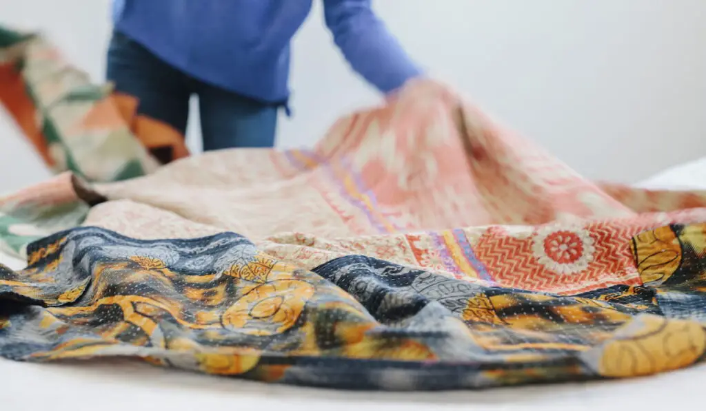 A woman spreading a fabric quilt 
