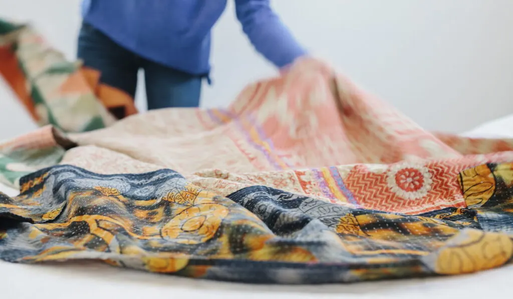 A woman spreading a fabric quilt 