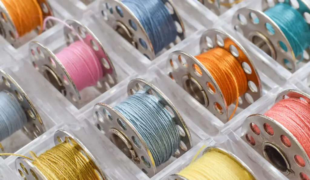 Closeup macro colorful sewing thread bobbins spools organized in tray