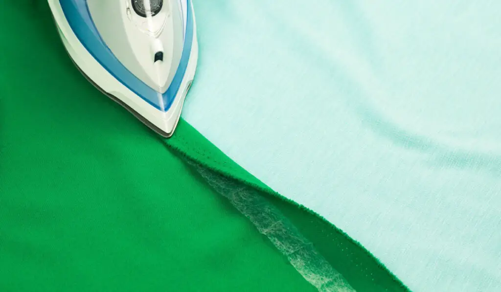 Hemming, shortening a green courtain fabric with an iron and the iron-on adhesive hemming tape 