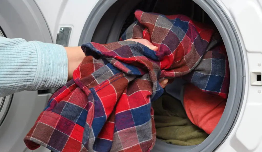 Woman puts clothes in washing machine