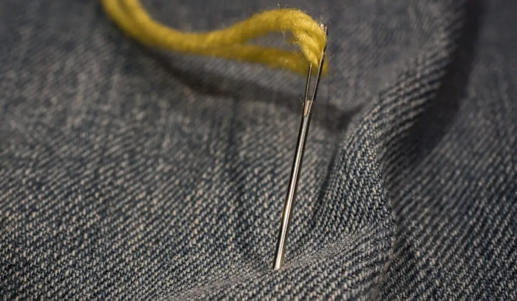 detail of yellow needle thread on jeans cloth