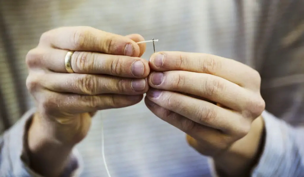 man holding a needle and thread