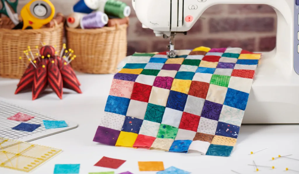 Colorful detail of quilt sewn from square pieces on sewing machine, quilting and sewing accessories