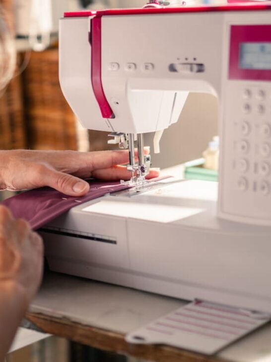 Seamstress runs a piece of fabric through the sewing machine - ee220920