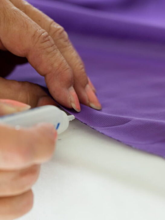 Woman's hands using fabric glue on purple garment - ss220920