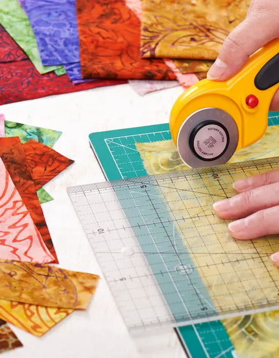 Process cutting fabric pieces by rotary cutter on mat