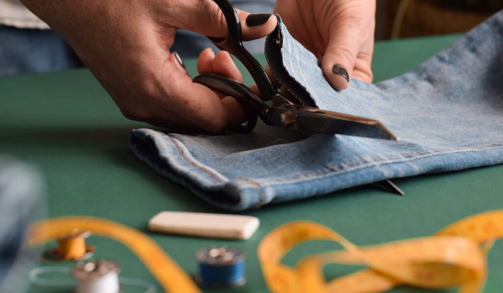 Seamstress cutting length of jeans pants to be hemmed