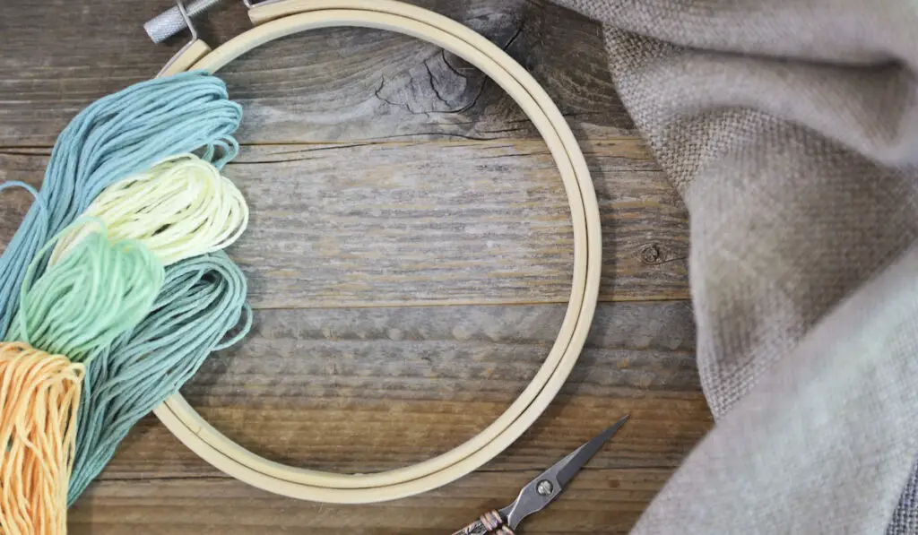 Colorful embroidery floss with hoop and vintage scissors on rustic wooden table