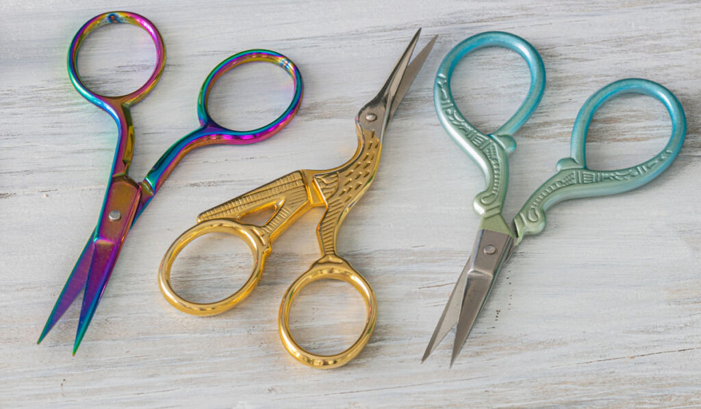 Colorful embroidery scissors on white wooden table