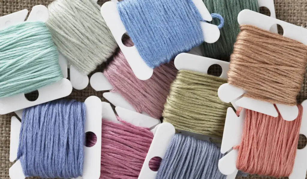 Embroidery floss on bobbins in pastel greens, blues and pinks.

