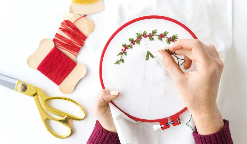 Hands making holly berries embroidery