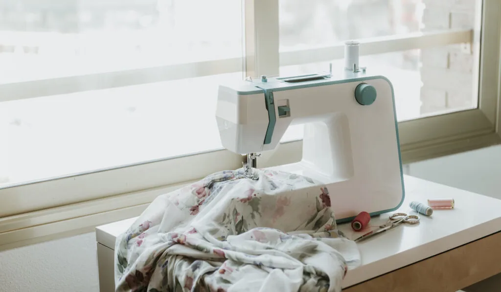 Modern sewing machine and window in dressmaker workshop