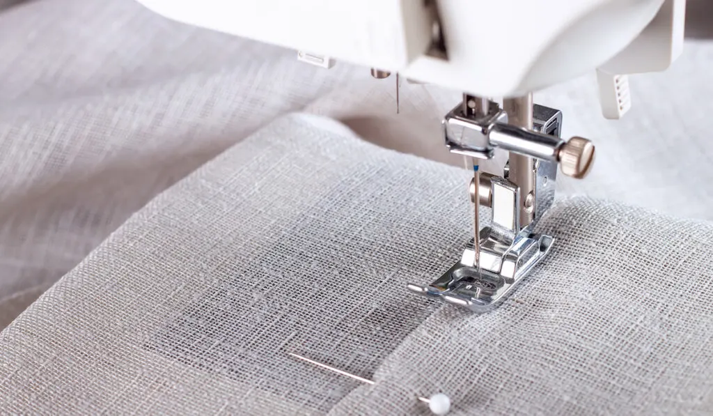 Modern sewing machine presser foot with linen fabric and thread