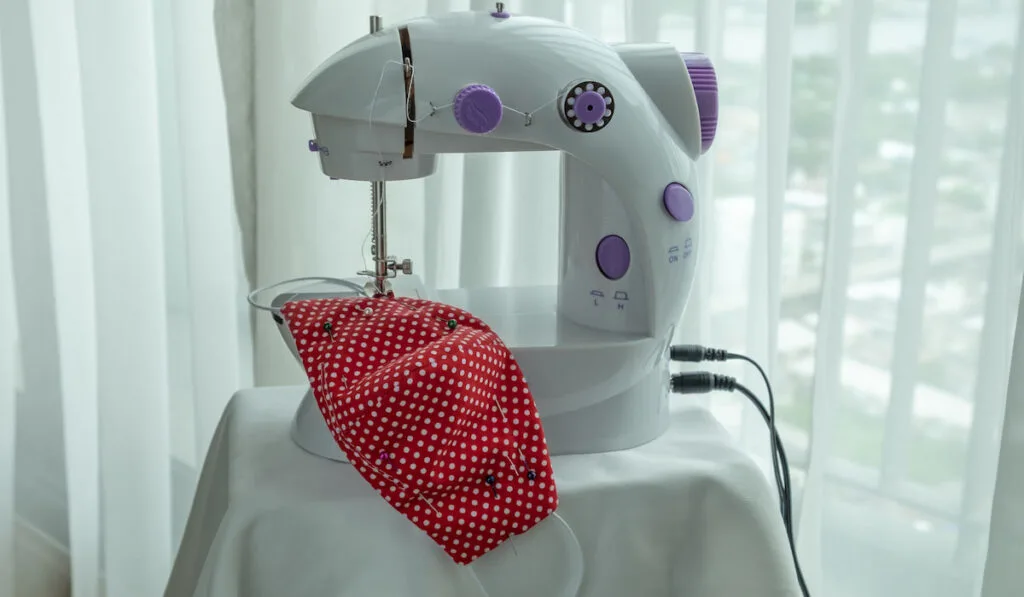 Sewing a red fabric face mask with a mini sewing machine
