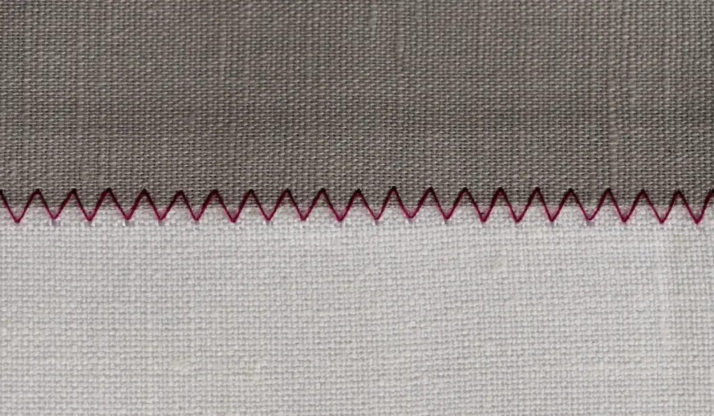 White and grey fabric stitched with a zigzag purple thread