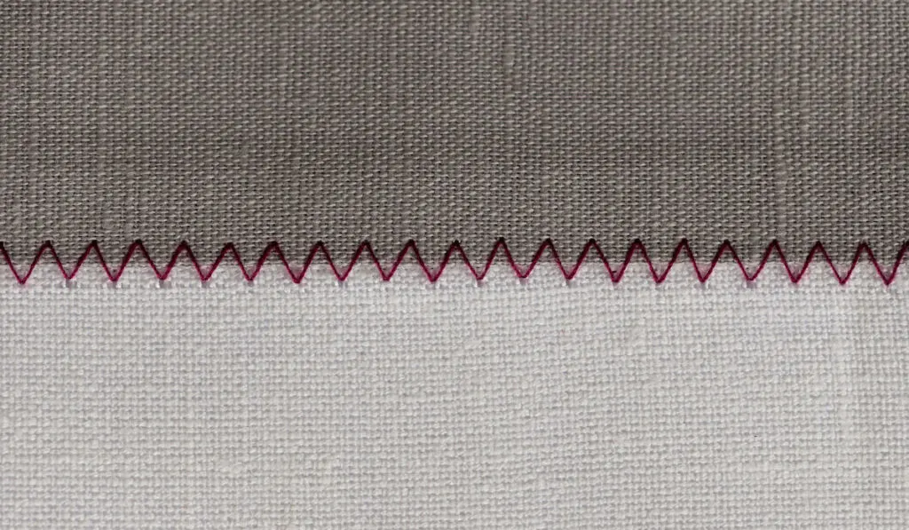 White and grey fabric stitched with a zigzag purple thread