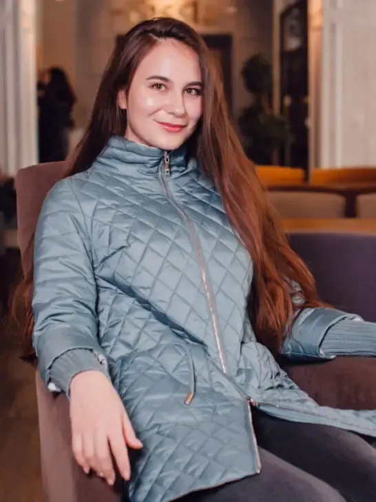 beautiful woman sitting on a chair wearing a quilted jacket