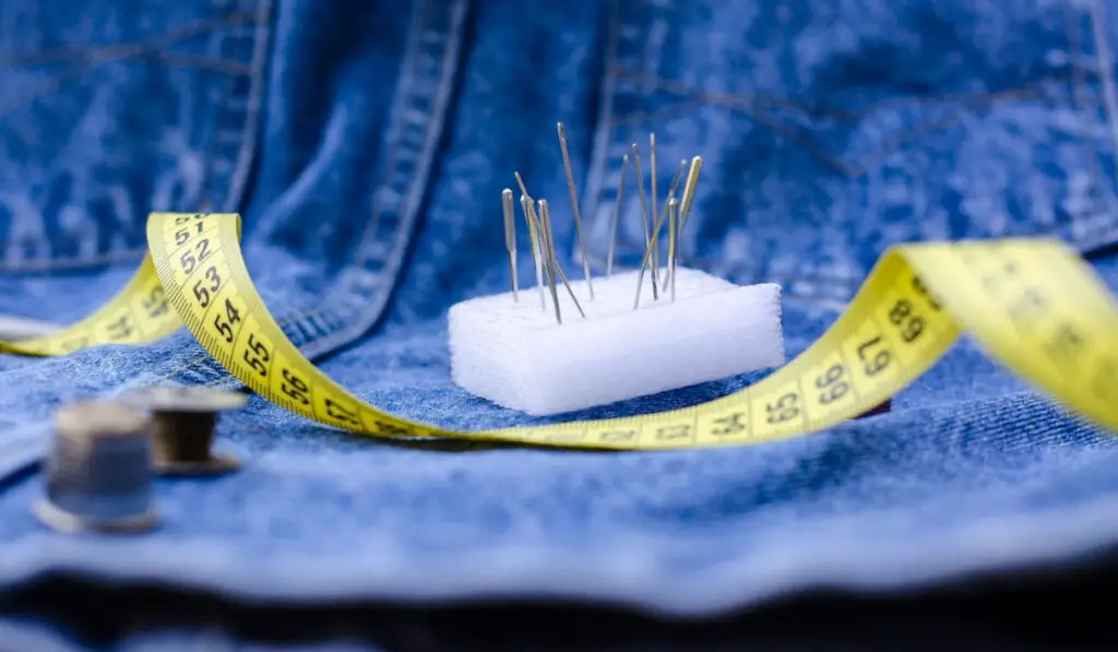 Centimeter and sewing pins on a denim