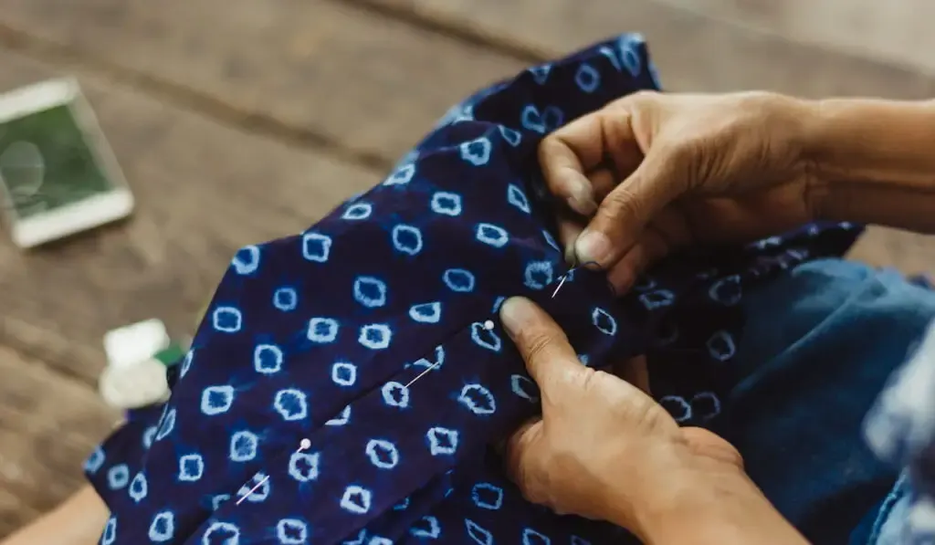hands sewing running stitch in blue tribal fabric