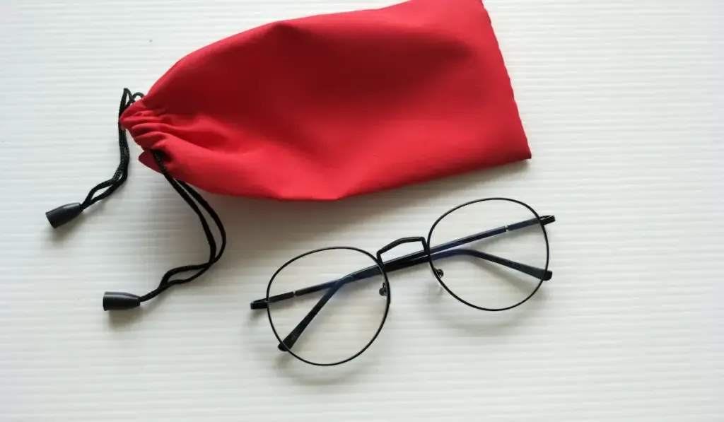 Eye glasses and red fabric case on white background
