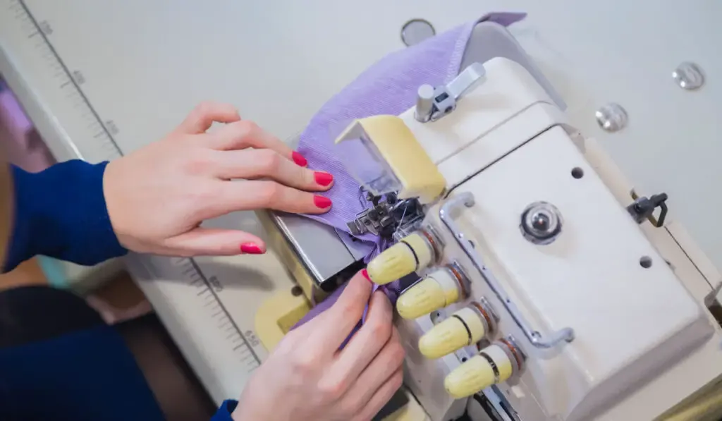 Professional tailor, top view seamstress using overlocking machine