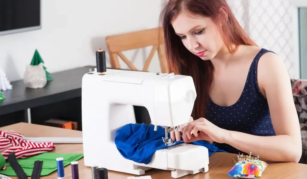 Young woman sewing shirt on sewing machine