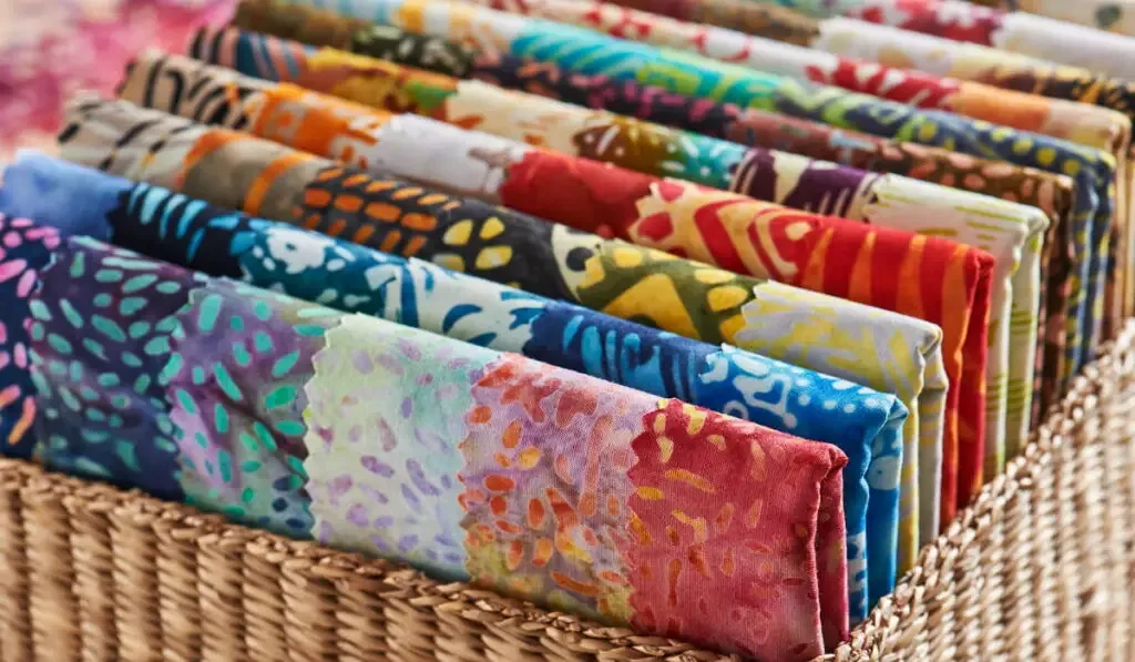 folded bright pieces of quilting batik fabrics in a basket,