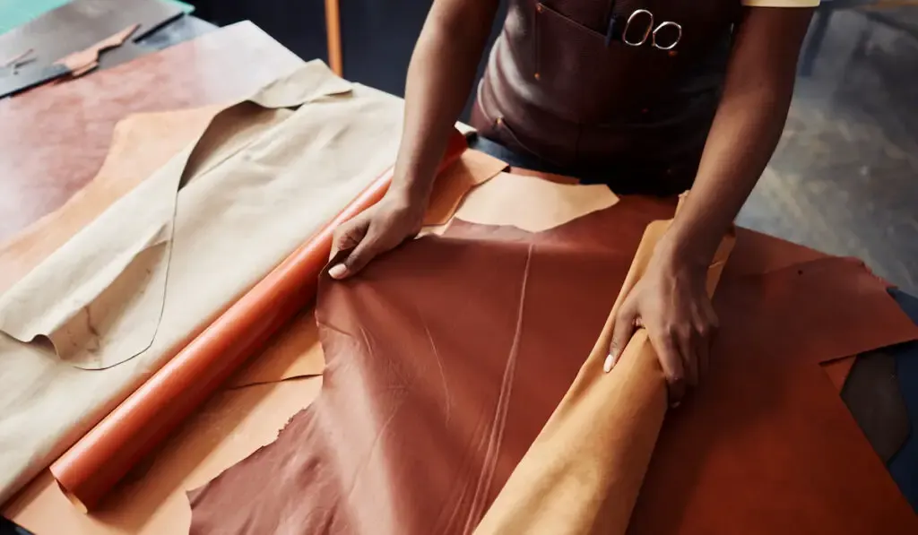 top view of female working with genuine leather in workshop