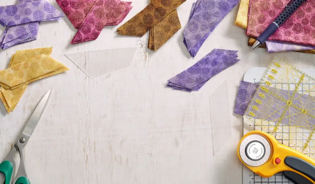 Stacks of multi-colored pieces of fabric with rotary cutter and scisors