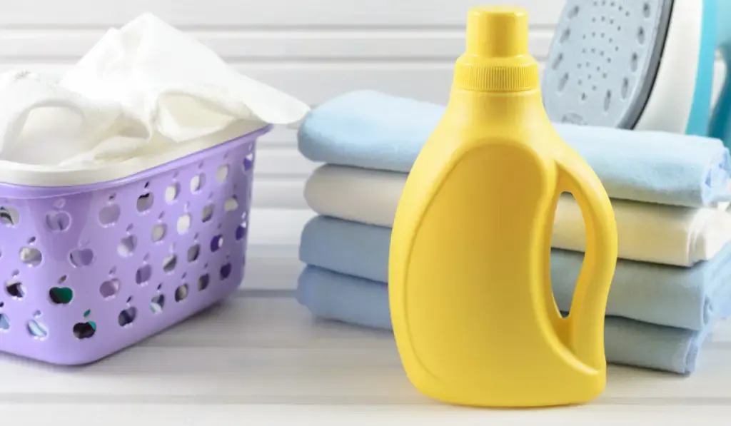 clean folded and ironed cloth, electric iron and blank yellow detergent bottle 