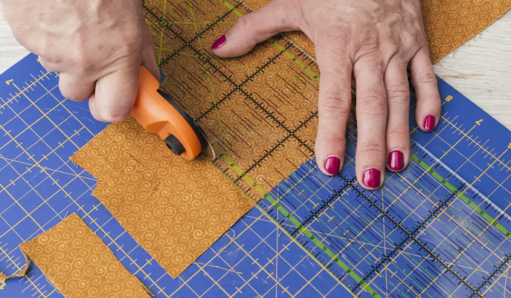 person cutting fabric pieces by rotary cutter